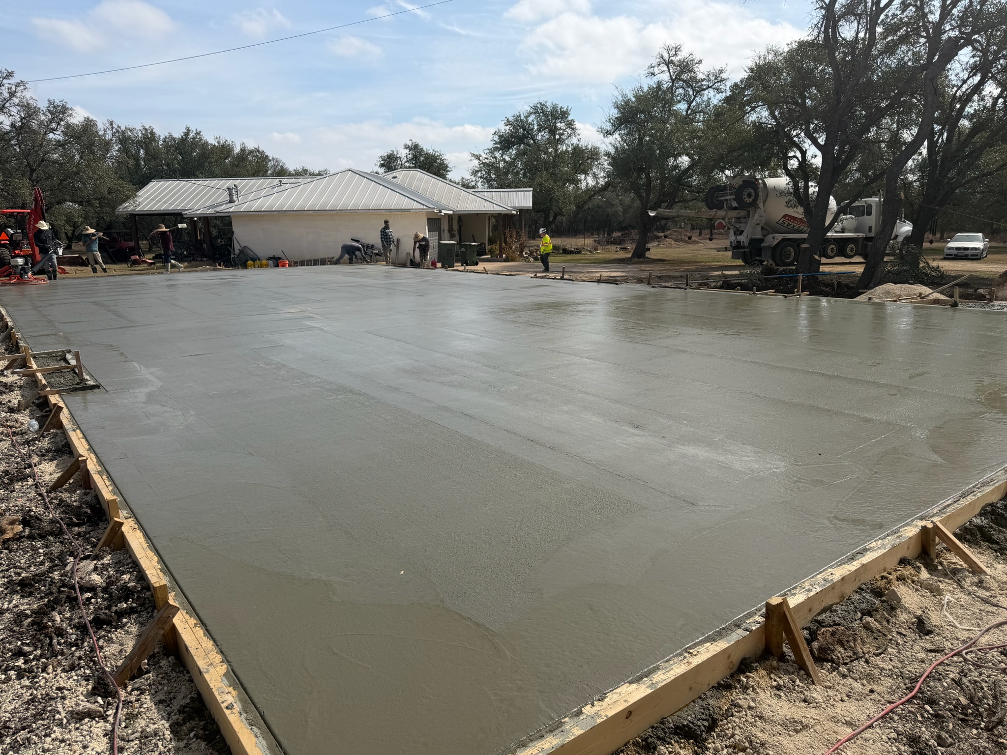 Wide view of a fresh concrete shop foundation slab near Georgetown with forms still set