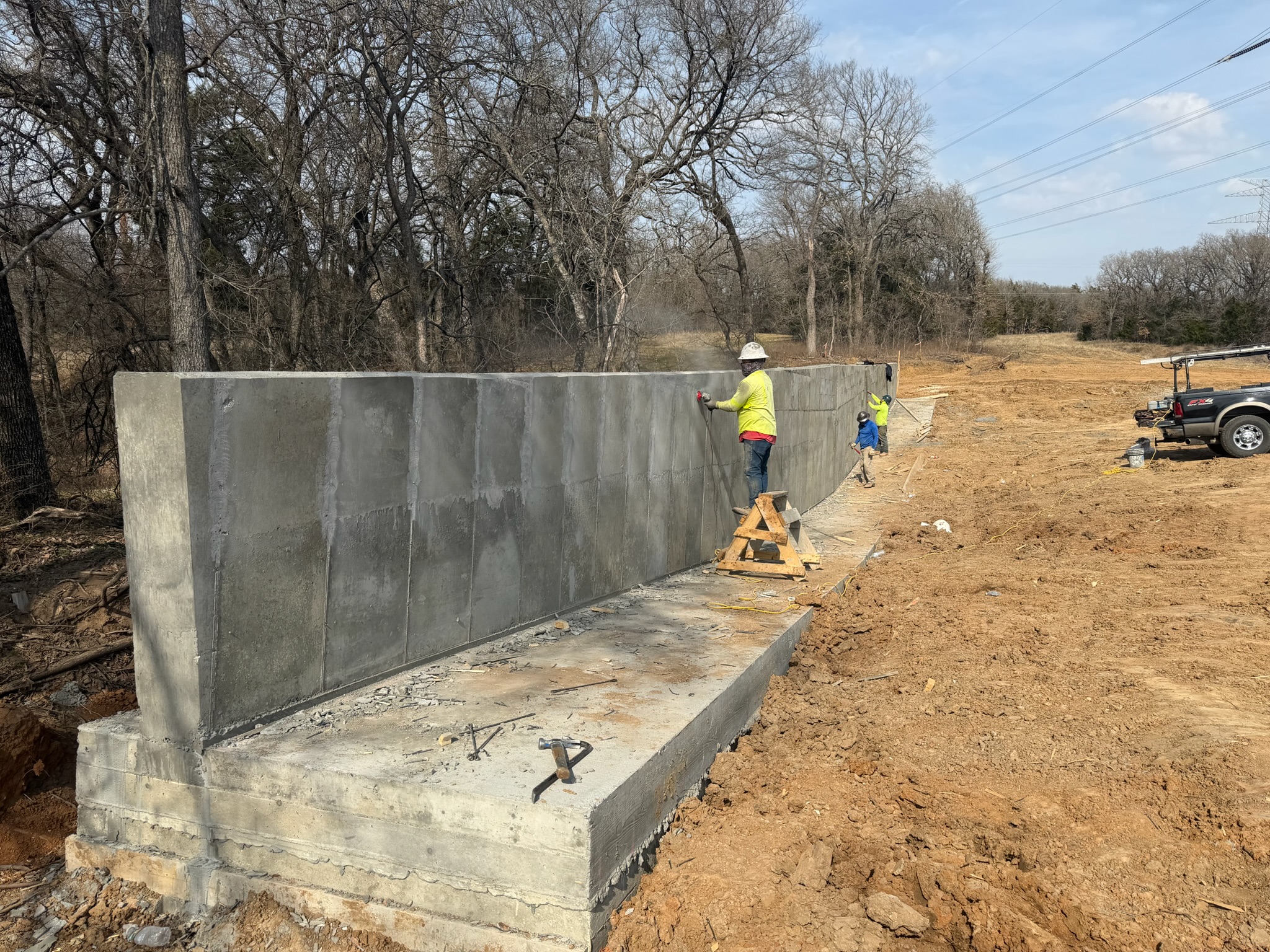 Long concrete retaining wall with dirt grading and power lines near Georgetown, Texas