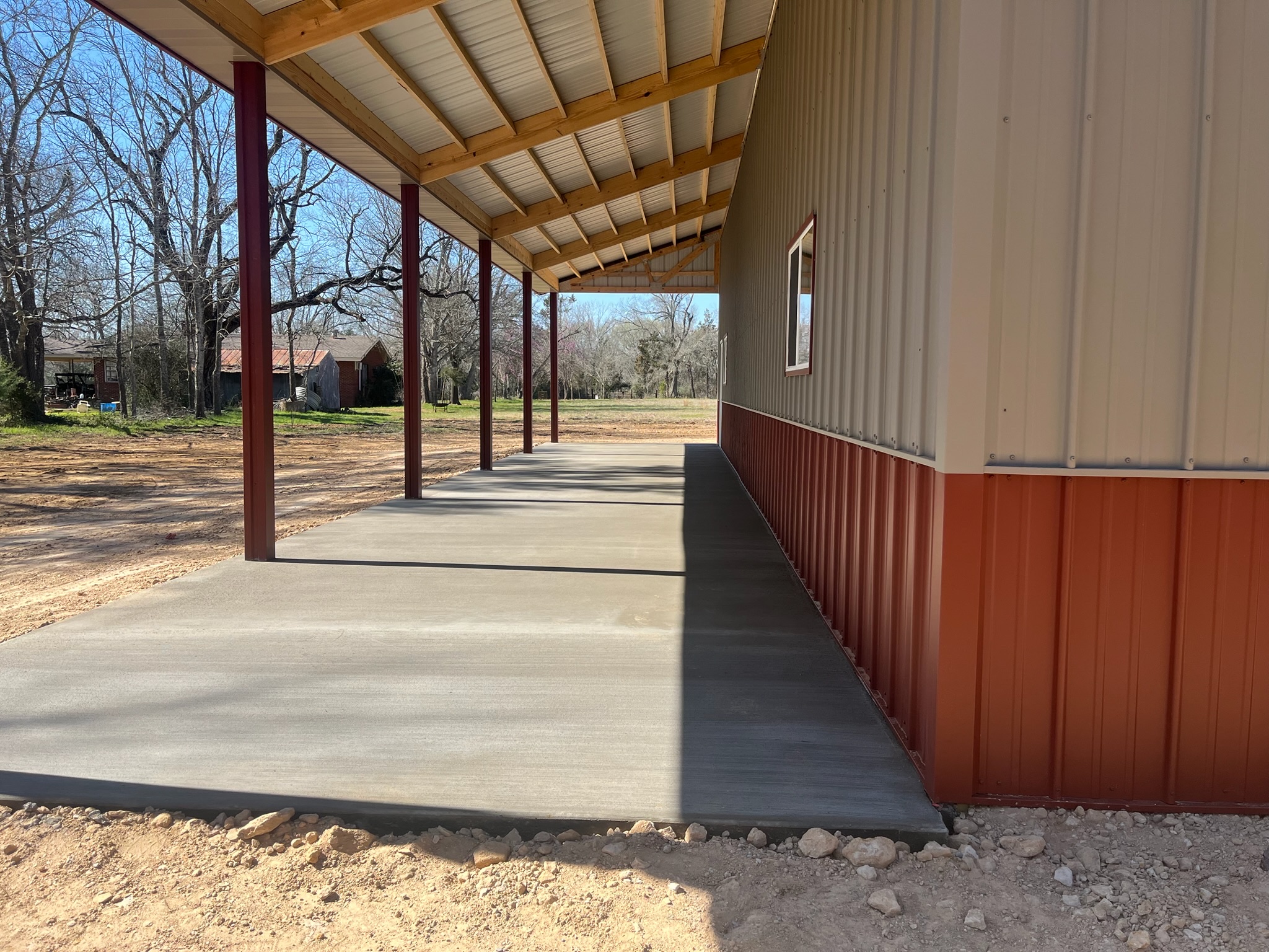 Covered exterior concrete apron beside a new metal shop building in Jewett, TX