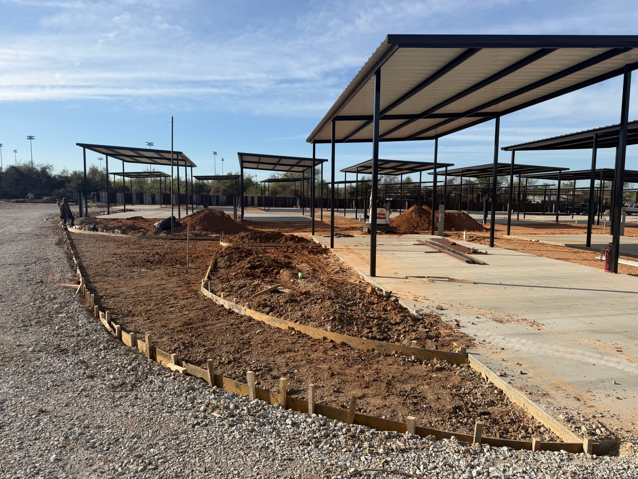 Fresh concrete pad, forms, and red dirt grading at the Magnolia RV site in Waco